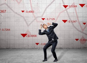 man cowering under declining stock market charts